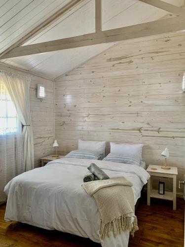 a bedroom with a large white bed with wooden walls at Eindelik on de Lange in Graskop