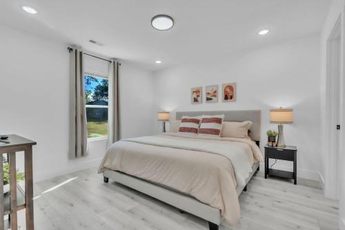 a white bedroom with a large bed and a window at 3 BR Downtown Spartanburg- Upscale& Work Ready "Sweet Carolina Cottage" in Spartanburg