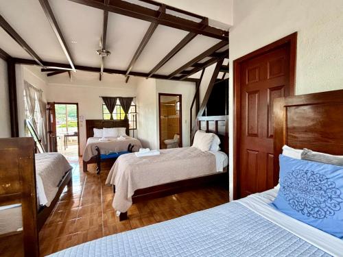 a bedroom with two beds with white sheets and blue pillows at Hotel & Restaurant Fleur de Lis in Concepción de Ataco