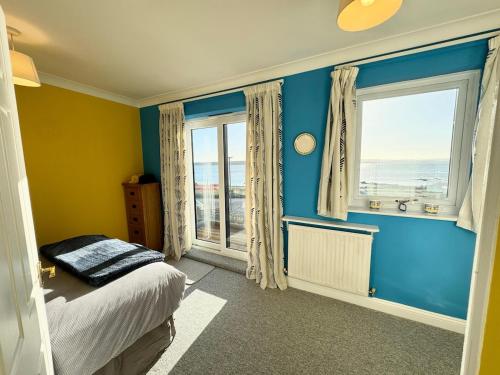 a bedroom with blue walls and a bed and a window at Poole Harbour View in Poole