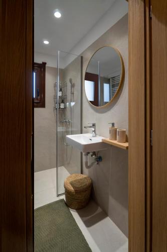 a bathroom with a sink and a shower with a mirror at Villa Olivia in Loutraki