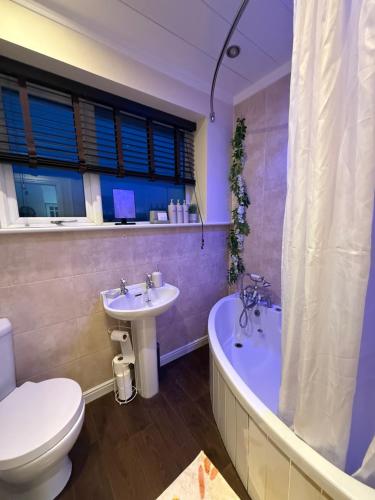 a bathroom with a toilet and a tub and a sink at Stunning 2 Bedroom Bungalow - Free Parking - Convenient Location in Cox Green