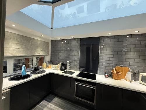 a kitchen with black cabinets and a large window at Stunning 2 Bedroom Bungalow - Free Parking - Convenient Location in Cox Green