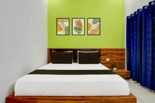 a bedroom with a large bed with blue curtains at Hotel O Adinath Guest House in Bahādrābād