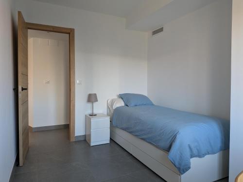 a white bedroom with a bed with a blue blanket at Apartamento Gandiaport in Gandía