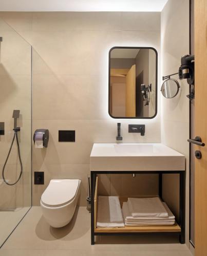 a bathroom with a toilet and a sink and a mirror at Hotel NOVA Inn Sarajevo in Sarajevo