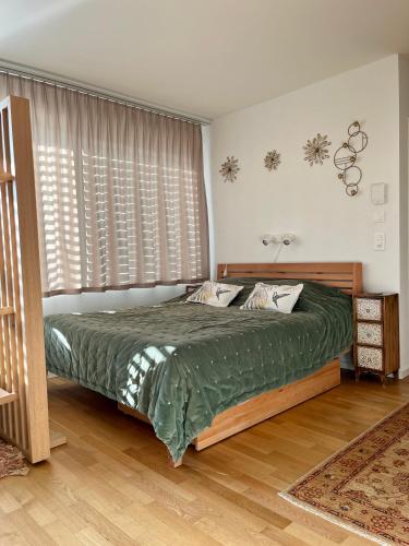 a bedroom with a bed with green sheets and windows at Studio Horizon Dorigny in Lausanne