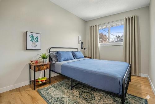 a bedroom with a bed with blue sheets and a window at Entire Home - 2 Separate Units in Calgary