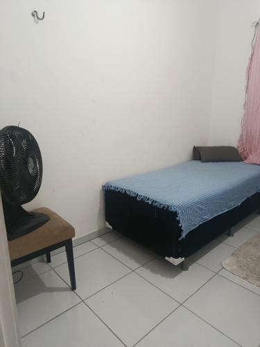 a bedroom with a bed and a chair and a fan at Rogerio AP Compartilhado in Caucaia