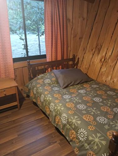 a bedroom with a bed with a bedspread with flowers at Cabañas Río Iculpe in Lago Ranco