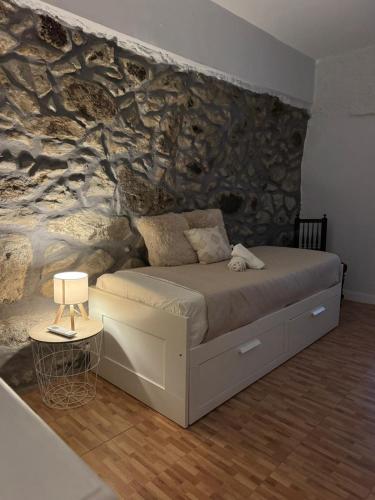 a bed in a room with a stone wall at Adoria GuestHouse in Adoria
