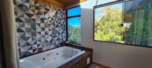 a bathroom with a large tub and two windows at Pousada Trinca Ferro in Bom Retiro