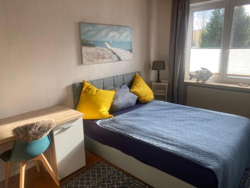a bedroom with a bed with yellow pillows and a desk at Apartment am Waldrand Nichtraucher gemütlich und ruhig in Itzehoe