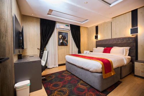 a hotel room with a large bed and a desk at Bourdillon Hotel and apartments in Gwarinpa