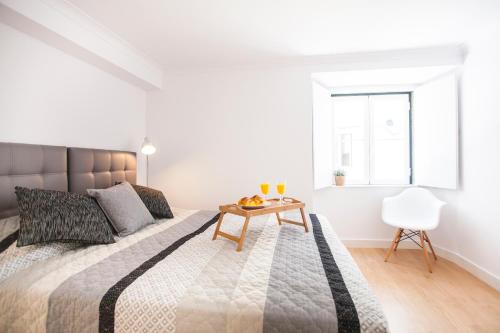 een witte slaapkamer met een groot bed en een houten tafel bij Light of Lisbon Apartments II in Lissabon