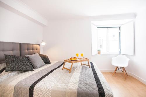 リスボンにあるLight of Lisbon Apartments IIの白いベッドルーム(大型ベッド1台、木製テーブル付)