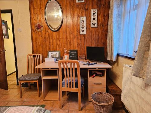 a desk with a computer on it with two chairs at Self contained 1 bedroomed garden flat in Abersychan