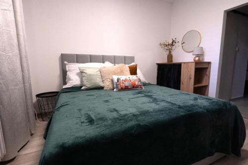 a bedroom with a large bed with a green blanket at Wittgruber's Upperroom in Koliba