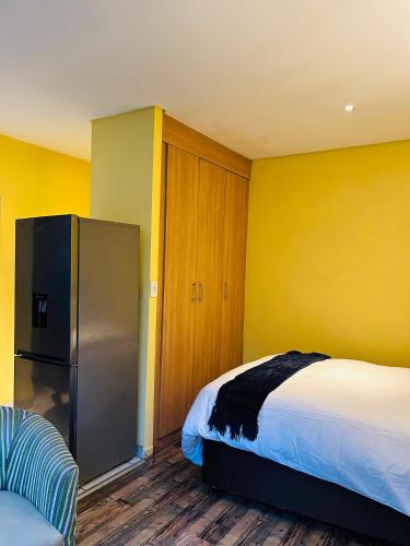 a bedroom with a bed and a refrigerator in it at Seven Eleven Apartments - Isibaya House in Johannesburg
