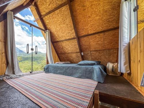 a bed in a room with a large window at Chalé Agulhas Negras in Resende