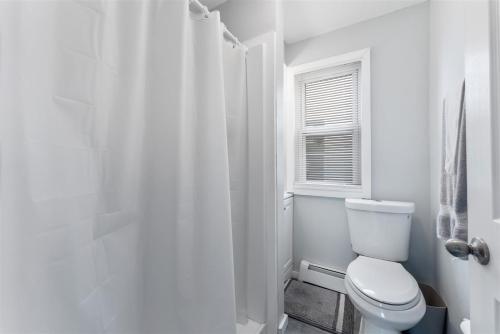 a white bathroom with a toilet and a window at 404 W Maple Ave, Unit A in Wildwood