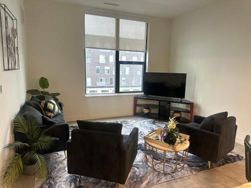 a living room with couches and a flat screen tv at Modern Downtown Detroit 2BR Retreat in Detroit