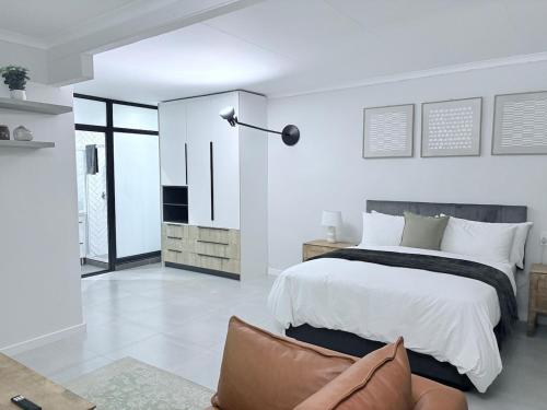 a white bedroom with a large bed and a couch at Canopy stay 4 in Sandton