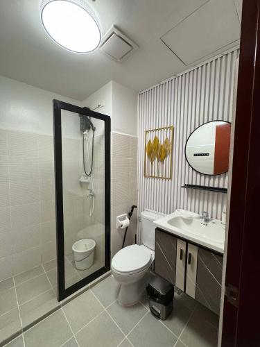 a bathroom with a toilet and a sink and a mirror at Ona's Condo in Bacolod