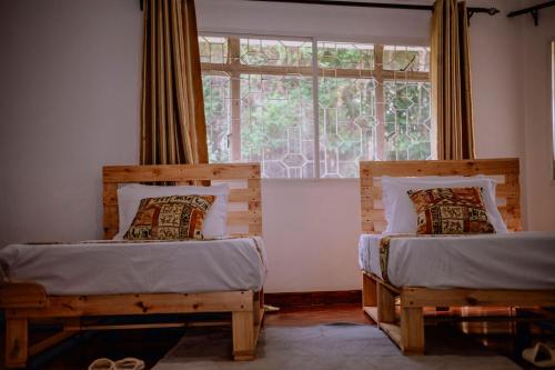 two beds in a room with a window at Avana Home in Arusha