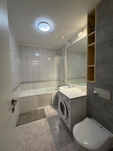a bathroom with a toilet and a tub and a washing machine at Sloth Room in Warsaw