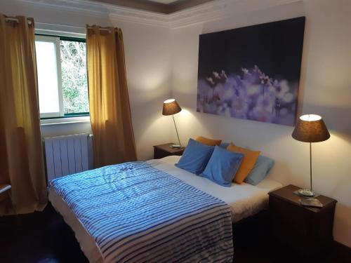 a bedroom with a bed with blue and orange pillows at At Home Sintra in Sintra