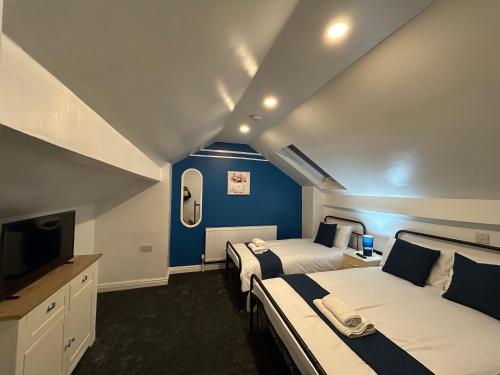 two beds in a room with blue walls and a tv at Minstead Houses - 5 Bedroom Contractor House Sleeps 9 Parking for 2 Vans Near Bromford Duddeston Fort Dunlop Star City HS2 in Birmingham