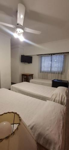 a bedroom with two beds and a ceiling fan at Necochea Real Hotel in Necochea