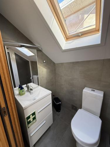 a bathroom with a toilet and a sink with a skylight at Casa Manuel in Manteigas