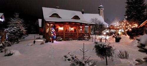 a log cabin with christmas lights in the snow at Tylickie Chałupy in Tylicz