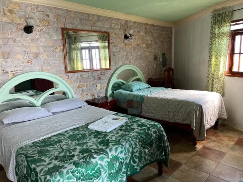 a bedroom with two beds and a mirror at Hotel Las Flores in Xalapa