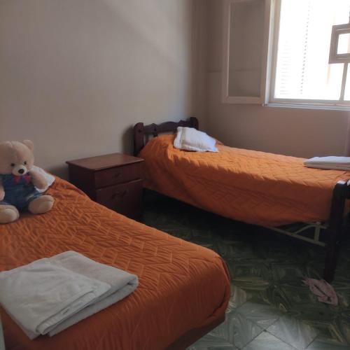a room with two beds with a teddy bear sitting between them at Chalet Ferrari in Mina Clavero