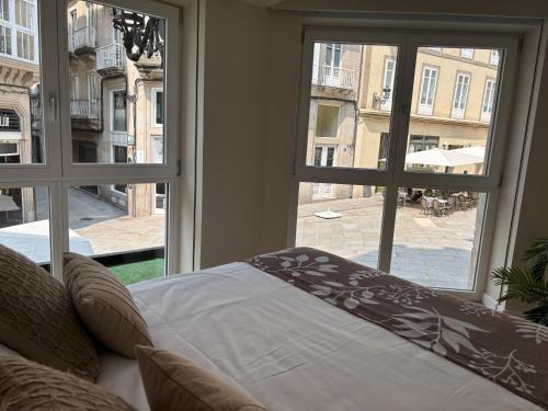 a bedroom with a bed looking out of a window at LAS TERRAZAS I Lujo frente a la plaza de Santa Eufemia in Ourense