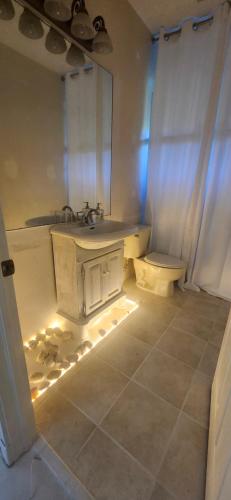 a bathroom with a sink and a toilet with lights at Ocean Spa Oasis in Port Saint Lucie