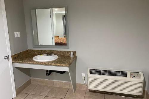 a bathroom with a sink and a mirror and a fan at Stay Inn Motel in Harbor City