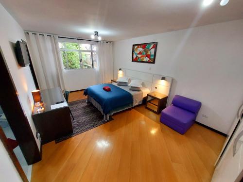 a bedroom with a blue bed and a purple chair at Pousada Casa Verde - Curitiba in Curitiba
