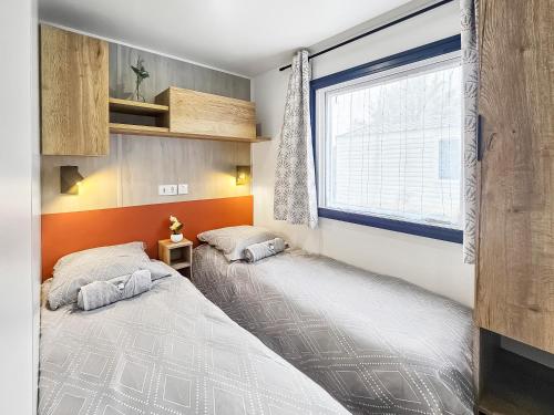two beds in a small room with a window at Séjour en Forêt 4 étoiles in Litteau