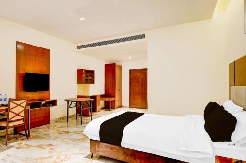 a bedroom with a bed and a desk and a television at Townhouse JFN Comfort Hotel in Chennai