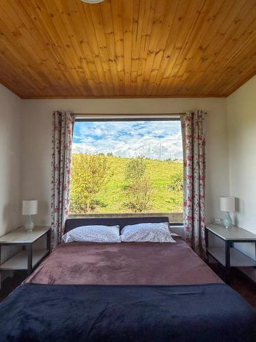 a bedroom with a bed and a large window at Finca Siberia, Sisga in Tilatá