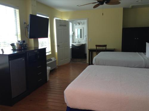 a hotel room with two beds and a flat screen tv at Ocean Village Hotel in Surfside Beach