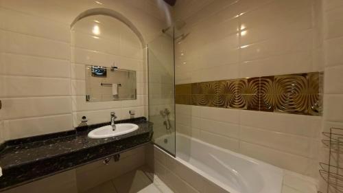 a bathroom with a sink and a bath tub at Golden Land in ‘Ezbet Abu Ḥabashi