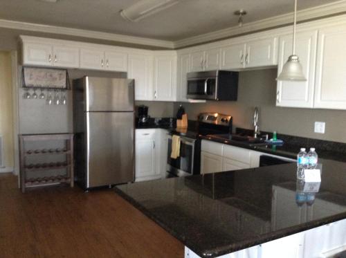 a kitchen with white cabinets and a stainless steel refrigerator at Ocean Village Hotel in Surfside Beach
