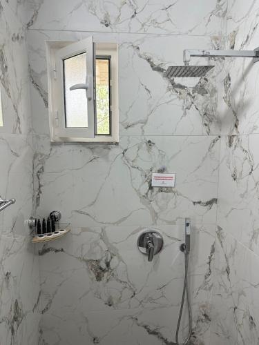 a marble bathroom with a sink and a window at Lexhulo Room's in Domje