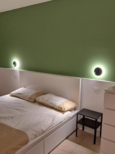 a bed with two pillows and a green wall at Borgo Piccolo in Imola