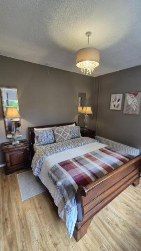 a bedroom with a large bed and a chandelier at Red Robin Cottage in Castlewellan